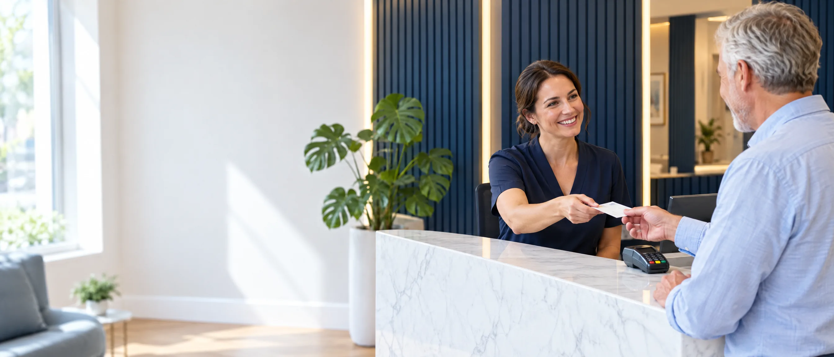 A receptionist handing a patient his appointment card at the Niva Medical Clinic front desk